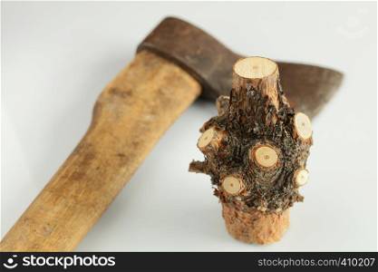 Part of a tree trunk with cut off branches on against the old ax on a white background. Nodal part of a tree trunk with cut branches and an old ax on a white background