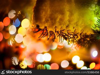 Part of christmas fir-tree under the snow outdoors with lights for design postcards