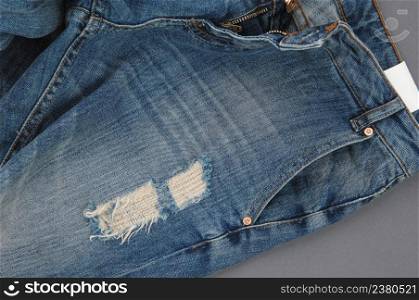 part of damaged denim pants with pocket and unbuttoned zipper, close-up. jeans close up
