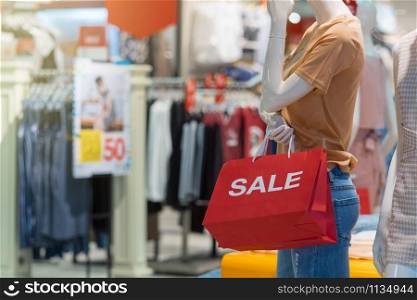 Part of female mannequin dressed in casual clothes holding the Sales paper shopping bag in the shopping department store for shopping, business fashion and advertisement concept