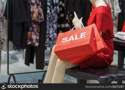Part of female mannequin dressed in casual clothes holding the Sales paper shopping bag in the shopping department store for shopping, business fashion and advertisement concept