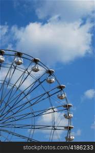 Part of Ferris wheel on blue sky background