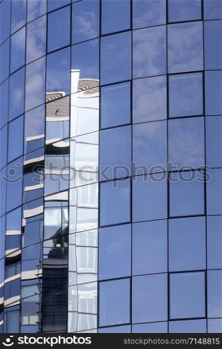 part of glass facade on modern office building reflecting blue sky