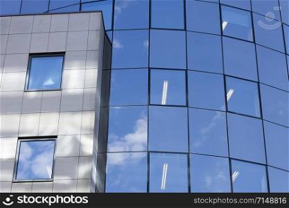 part of glass facade on modern office building reflecting blue sky