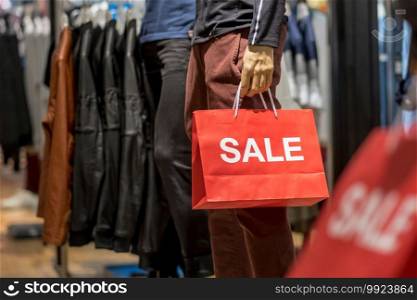 Part of male mannequin dressed in casual clothes holding the Sales paper shopping bag in the shopping department store for shopping, business fashion and advertisement concept