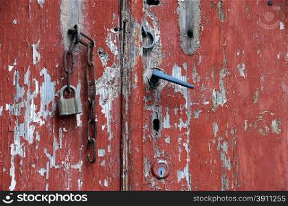 Part of red aged shabby door with rusty chain