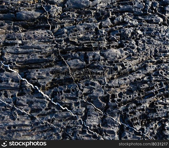Part of rock closeup with white stripes of another geological material. Nature background.
