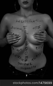 part of the body of a young girl with the inscription, humiliation, bullying, freedom, racism, violence . the captions are written in the photographer&rsquo;s hand, not in a tattoo . black and white photo.