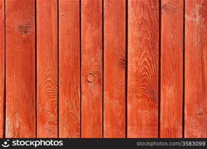 Part of vertical ancient wooden fence painted in red. Fine sunny weather