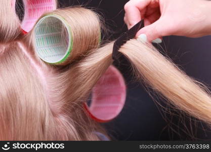 Part of woman. Blond girl with hair curlers rollers by hairdresser in hairdressing beauty salon. Hairstyle.