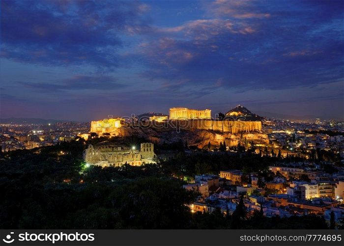 Parthenon Temple and Amphiteater are the antique iconic greek tourist landmark at the Acropolis of Athens and ancient European civilization architecture. View from Philopappos Hill at night. Greece. Parthenon Temple and Amphiteater are ancient architecture at the Acropolis, Athens, Greece