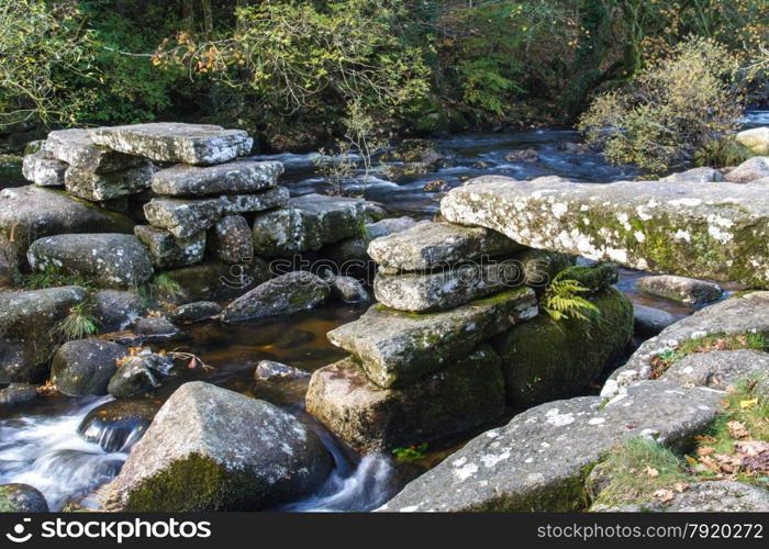 Partially collapsed ancient stone clapper bridge. Dartmeet, Dartmoor National Park, Devon, England, United Kingdom. Granite Bridge, autumn, fall, long exposure.