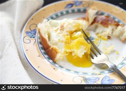 partially-eaten breakfast of eggs and bread on decorative plate