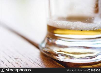 Partially Empty Cold Glass Of Beer With Frothy Foam And Bubbles On Rough Wooden Table