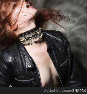 Partially nude Caucasian woman in leather jacket with long hair blowing.