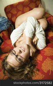 Partially nude Caucasian young adult woman lying upside down smiling and looking at viewer.