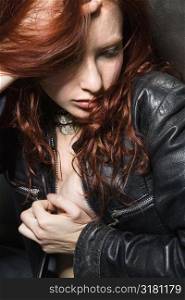 Partially nude redhead woman wearing leather jacket.