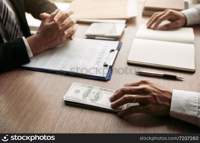 Partner has made a fraud in the contract of sale and being handed a cash and pen to the businessman signing the contract corruption bribery concept.