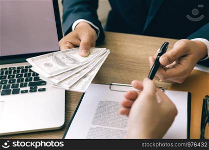 Partner has made a fraud in the contract of sale and being handed a cash and pen to the businessman signing the contract corruption bribery concept.