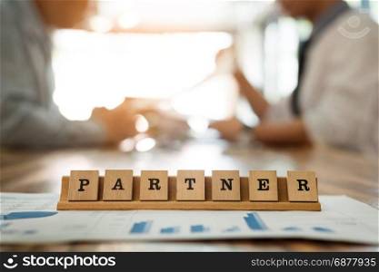 partner word on wood table with business man discuss for work during a meeting in the office, team work concept in background.