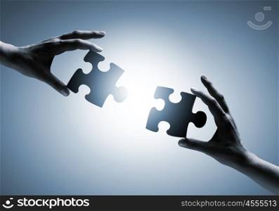 Partnership concept. Close up image of hands connecting puzzle elements