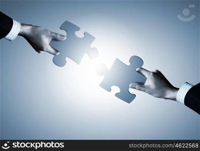 Partnership concept. Close up image of hands connecting puzzle elements