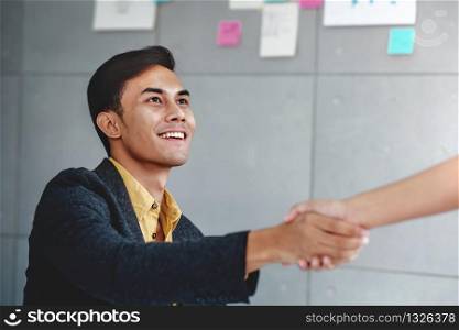 Partnership Concept. Happy Young Businessman in Office Meeting Room Handshake and Smiling with his Business Partner. Successful and Cooperation