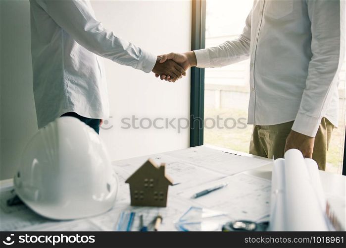Partnership engineering man with construction worker greeting shaking hand a foreman at renovating apartment.