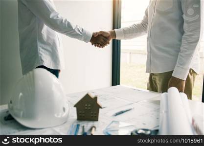 Partnership engineering man with construction worker greeting shaking hand a foreman at renovating apartment.
