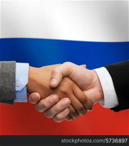 partnership, politics, gesture and people concept - close up of handshake over russian national flag background