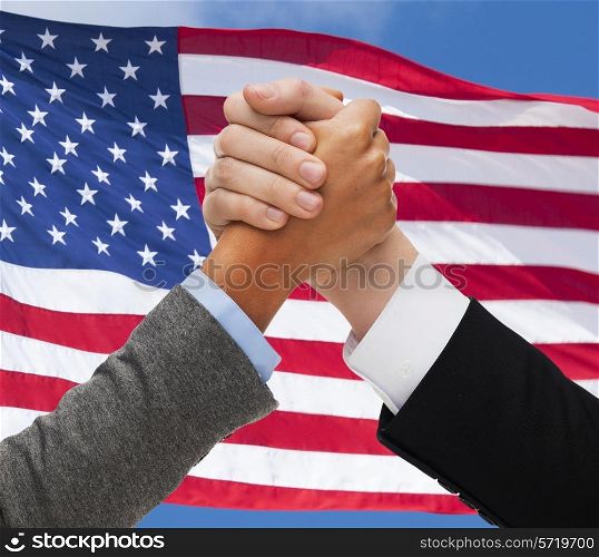 partnership, politics, gesture and people concept - close up of two hands armwrestling over american flag