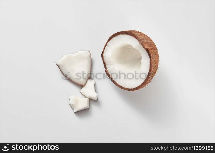 Parts of fresh natural organic tropical fruits coconut on a light grey background with copy space. Vegetarian concept.. Top view of fresh natural organic coconut&rsquo;s half on a light grey background.