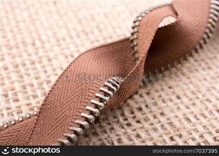Parts of the brown color zipper on linen canvas background