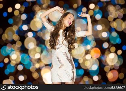 party and people concept - happy young woman dancing over festive lights background. happy young woman dancing over party lights