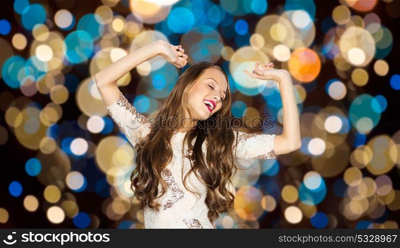 party and people concept - happy young woman dancing over festive lights background. happy young woman dancing over party lights