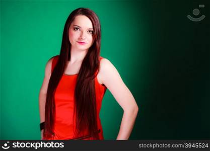 Party, celebration and date concept. Attractive young log hair woman in red dress on green background. Studio shot.