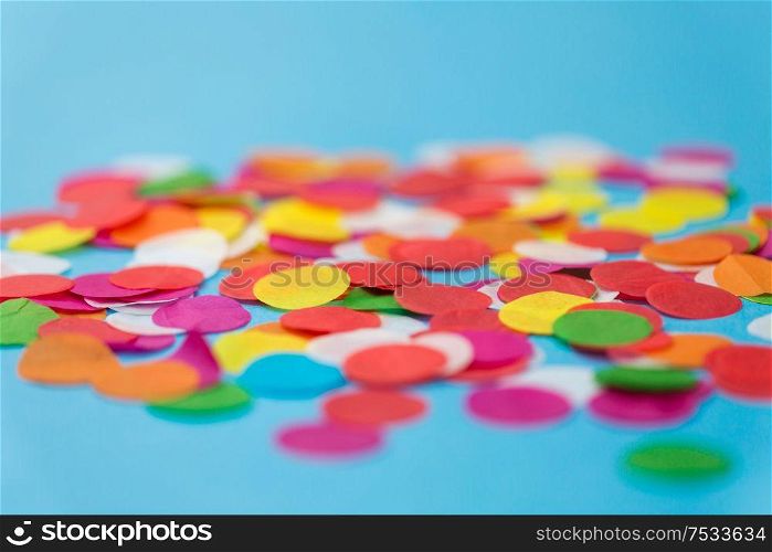 party, celebration and decoration concept - colorful confetti on blue background. colorful confetti decoration on blue background