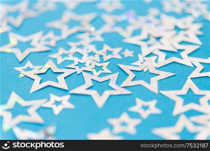party, celebration and decoration concept - holographic star shaped confetti on blue background. star shaped confetti decoration on blue background