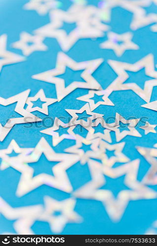 party, celebration and decoration concept - holographic star shaped confetti on blue background. star shaped confetti decoration on blue background