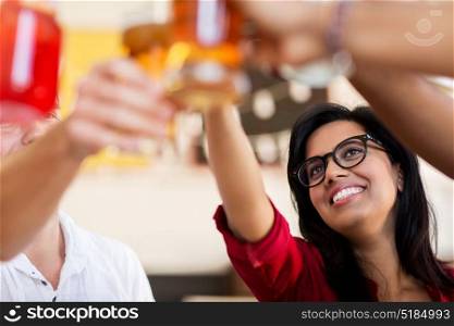 party, celebration and people concept - group of happy international friends clinking drink glasses at restaurant table. friends clinking glasses with drinks at restaurant
