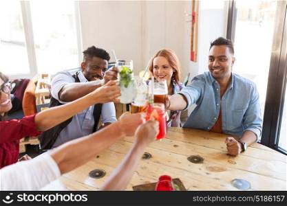 party, celebration and people concept - group of happy international friends clinking drink glasses at restaurant table. friends clinking glasses with drinks at restaurant