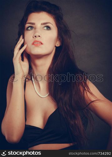 Party celebration concept. Magnificent long hair woman red lipstick wearing black evening dress pearls necklace on dark. woman in sensual black dress on dark