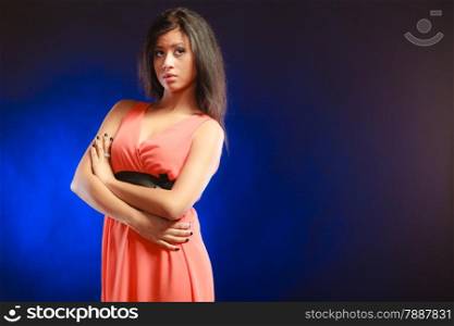 Party clothing evening fashion concept - Portrait attractive fashion woman, mixed race girl in orange elegant dress dark blue background. Copy text space