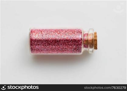 party, decoration and holidays concept - red glitters in small glass bottle with cork stopper over white background. red glitters in bottle over white background
