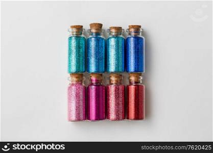 party, decoration and holidays concept - set of different color glitters in small glass bottles with cork stoppers over white background. set of glitters in bottles over white background