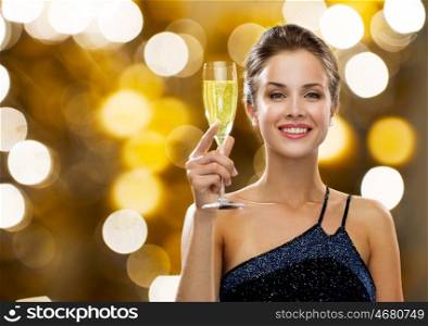 party, drinks, holidays, luxury and celebration concept - smiling woman in evening dress with glass of champagne over lights background