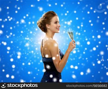 party, drinks, holidays, luxury and celebration concept - smiling woman in evening dress with glass of sparkling wine over blue snowy background
