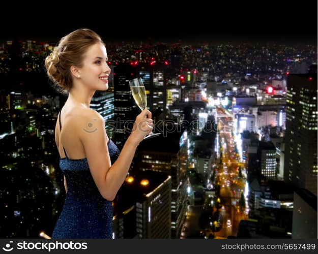 party, drinks, holidays, luxury and celebration concept - smiling woman in evening dress with glass of sparkling wine over night city background