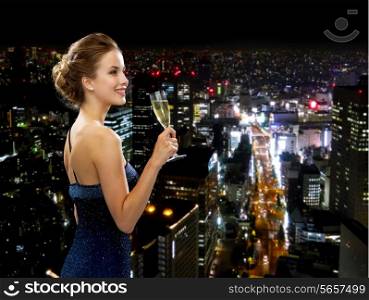 party, drinks, holidays, luxury and celebration concept - smiling woman in evening dress with glass of sparkling wine over night city background