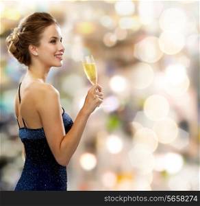 party, drinks, holidays, luxury and celebration concept - smiling woman in evening dress with glass of sparkling wine over lights background